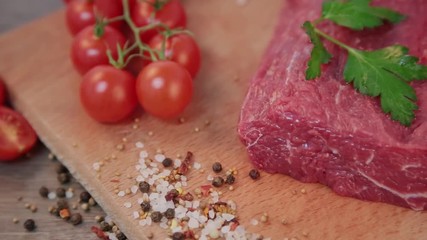 Wall Mural - raw beef on a wooden background with spices and tomatoes.