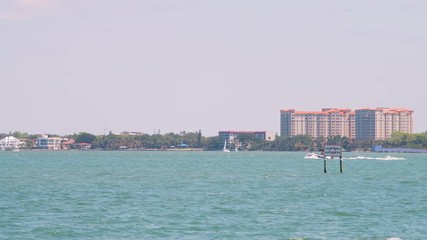 Wall Mural - Sarasota, USA Beach panning on Florida city during sunny day with cityscape by bay buildings and boat swimming by sign in harbor