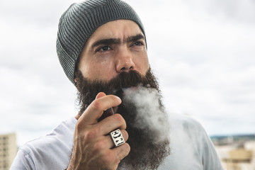 Wall Mural - Stylish bearded man smoking pipe looking at the horizon from the top of a tall building.