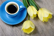 cup of coffee and tulips on wooden table. top view