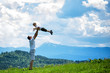 © somemeans - Happy father throws up a little son against a background of green forest, mountains and sky with clouds. Paternity friendship