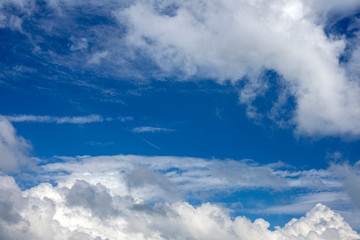 Airplane trail in the blue cloudy sky.