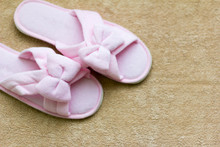 Pink Soft Slippers With A Bow Stand On A Beige Rug