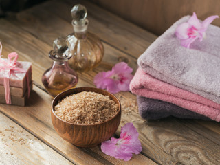 Sea salt, natural handmade soap, natural cosmetic oil and colorful towels with azalea flowers on rustic wooden background