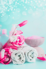 Wall Mural - spa towels with pink flowers at light blue background with bokeh. beauty concept