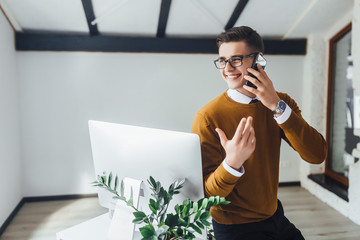 Wall Mural - Positive businessman with laptop and smartphone always has access to internet. White office .