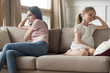 © fizkes - Stubborn mother and child girl sitting turned away on sofa