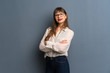 © luismolinero - Woman with glasses over blue wall with arms crossed and looking forward