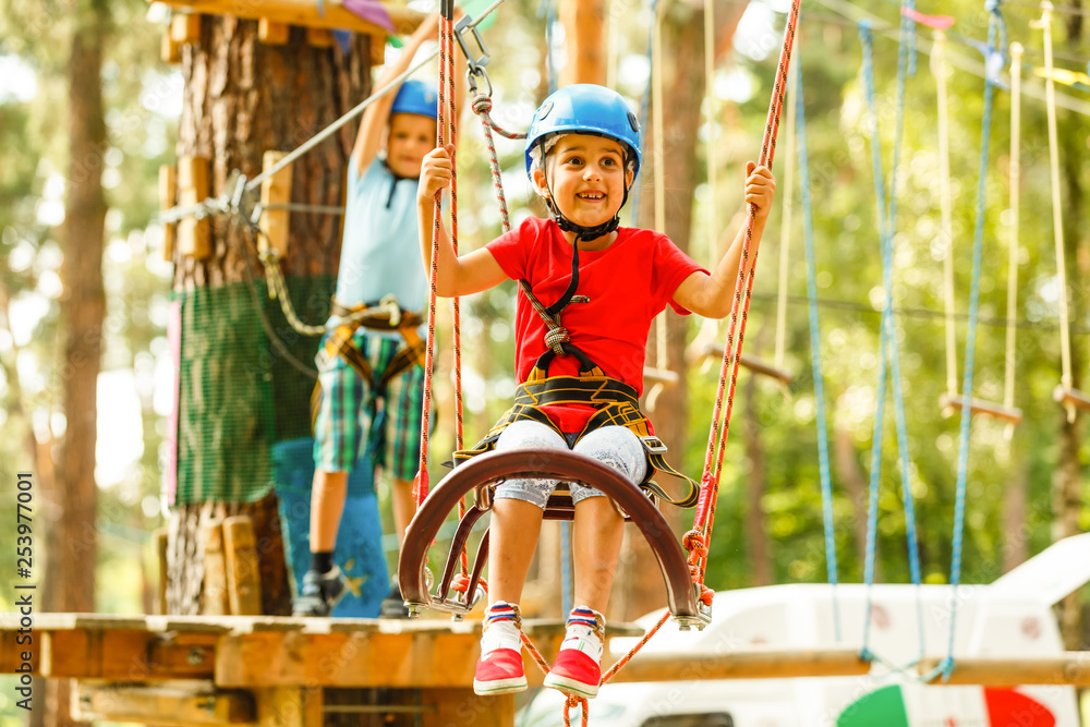 Children - a boy and a girl in the rope park pass obstacles. Brother ...