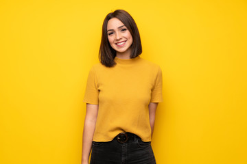 young woman over yellow wall smiling