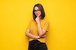 canvas print picture - Young woman over yellow wall with glasses and smiling