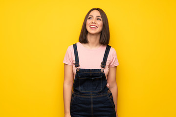 Wall Mural - Young woman over yellow wall smiling