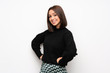© luismolinero - Young woman over white wall posing with arms at hip and smiling