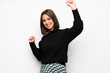 © luismolinero - Young woman over white wall celebrating a victory in winner position