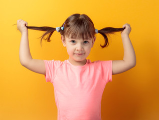 Four-year-old girl in a pink t-shirt on an orange background.