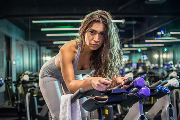 Wall Mural - Beautiful woman exercising on indoor bike during cardio training in gym