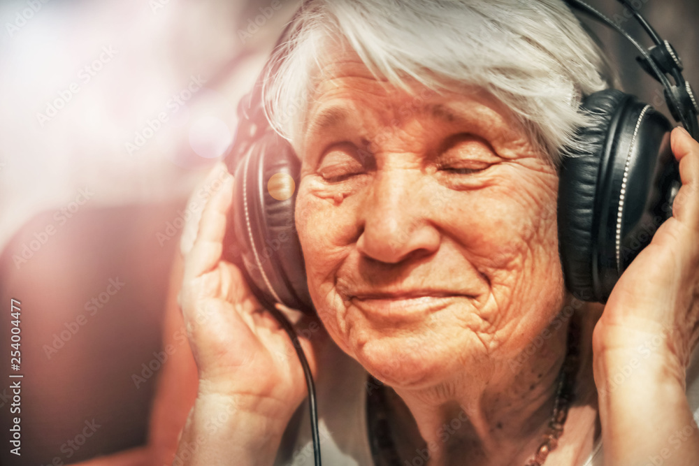 old woman in headphones listening to music - obrazy, fototapety, plakaty 