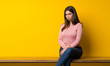 © luismolinero - Young woman sitting on table with sad and depressed expression