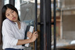 © saksit - Portrait of Asian girl enter door to coffee shop .Businesswoman using phone and walking to cafe