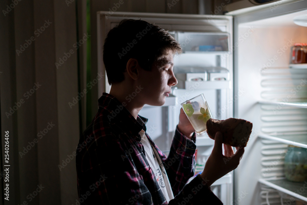 teenager eat junk food near fridge at night