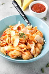 Canvas Print - Pasta conchiglioni (conchiglie, shells) with tomato sauce, Parmesan cheese and thyme in a blue plate on a gray background. Delicious healthy vegetarian food, Italian cuisine