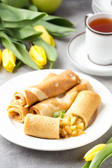 Wall Mural - Thin pancakes (crepes) with apple filling, stuffed rolls, Russian traditional food for maslenitsa, French dessert, breakfast with tulips on mother's day