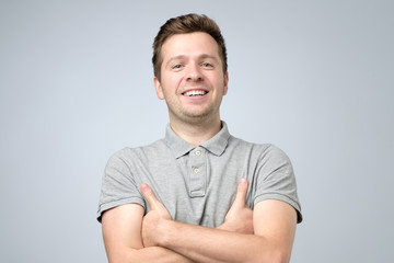 Sticker - young handsome smiling man in t-shirt standing with crossed hands.