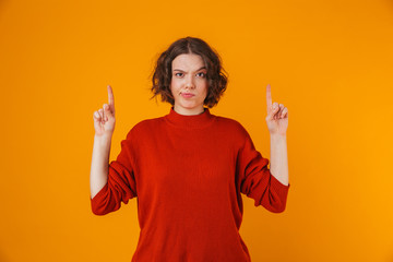 Wall Mural - Confused young pretty woman posing isolated over yellow wall background pointing.