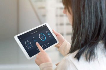Aufkleber - Woman control temperature in living room with smart home control app on tablet. View from the shoulder. Tehnology automation concept.