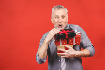 Omg! Portrait, happy super excited senior man, opened, unwrapped gift boxes, isolated against red background, enjoying his present.