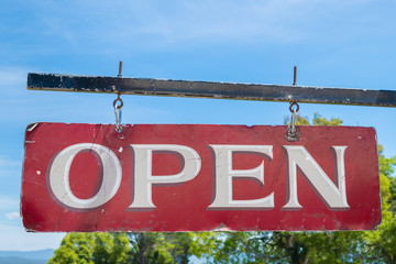 Open business old red and white vintage sign hanging from black metal pole