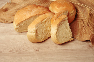 Two loafs of white bread, canvas and ears on a wooden table