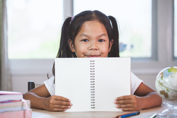 Back to school. Cute asian child girl holding a book in the classroom