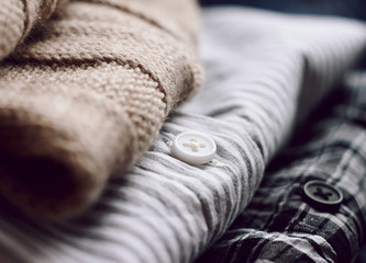 A neat stack of clothes - a beige scarf and two shirts. One plaid shirt, the other striped.