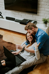 Wall Mural - Close up of a couple using a notebook while sitting on the floor in their living room