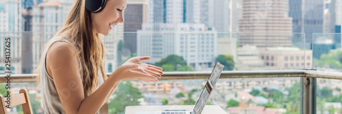 Young woman teaches a foreign language or learns a foreign language on the Internet on her balcony against the backdrop of a big city. Online language school lifestyle BANNER, LONG FORMAT