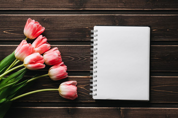 Wall Mural - pink flowers tulips with blank Notepad on wooden table for greeting card