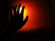 © Wararat - The woman's left hand with yellow light has a red background. The middle of the dark atmosphere.