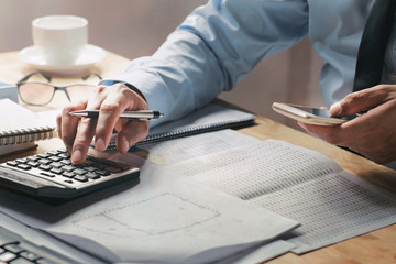 Fototapete - businessman working on desk in office using calculator and mobile
