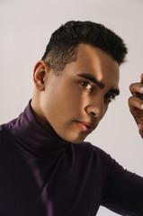 Wall Mural - Dark skinned fashion model posing for pictures in studio isolated on white background. Close up portrait of attractive African American man with emotional face in stylish purple turtleneck