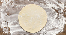 Raw Rolled Out Pizza Dough On Floured Surface