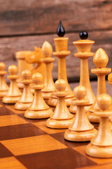 Wall Mural - Wooden chess figures on chess board. Wooden cheese pieces including queens and pawns. How to set up a chess game.