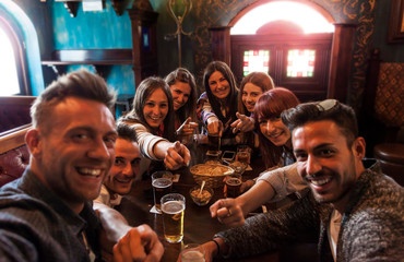 group of people celebrating in a pub drinking beer