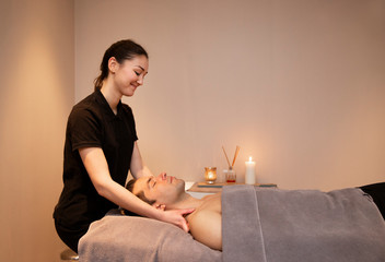 Man getting a massage by a woman in warm environments. Spa and wellness.