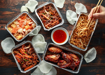 Wall Mural - Chinese takeaway food. Crispy shredded beef, sweet and sour chicken wings, egg noodles with bean sprouts, pineapple, chilli dip and prawn crackers