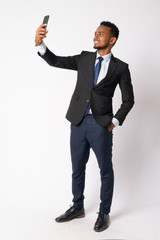 Wall Mural - Full body shot of happy young handsome African businessman taking selfie