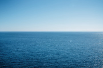 clean blue sky above a blue surface of the sea.