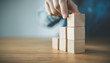 © oatawa - Hand arranging wood cube stacking as step stair. Business concept growth success process, copy space.