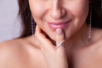 Closeup beautiful brunette girl with long hair in modern silver jewelry earrings, rings, bracelet, chain, necklace. Сoncept shooting store gentle, elegant, delicate, romantic bijouterie on model