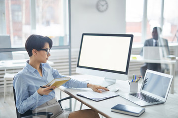 Busy young office worker with notebook thinking of organization point while reading document by workplace